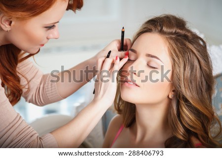 makeup artist preparing bride before the wedding in a morning