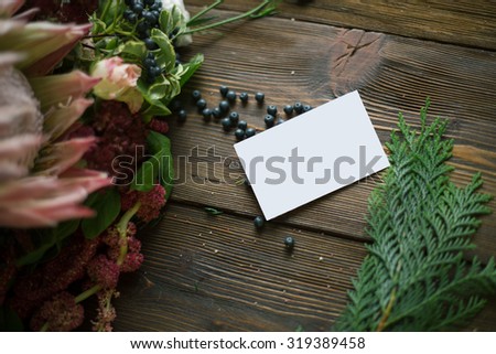 Florist workplace: visit card and flowers and accessories on a vintage wooden table. soft focus