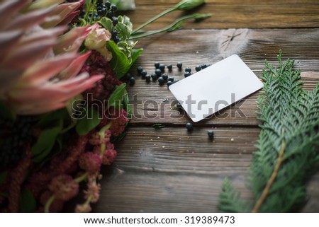 Florist workplace: visit card and flowers and accessories on a vintage wooden table. soft focus