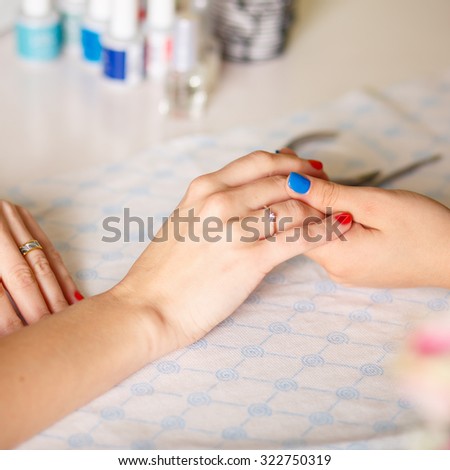 Closeup shot of a woman in a nail salon receiving a manicure by a \
\
beautician with nail file. Woman getting nail manicure. Beautician file \
\
nails to a customer.