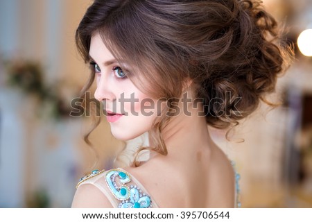 Close-up portrait of beautiful young lady in a luxury blue dress with perfect makeup and hair style