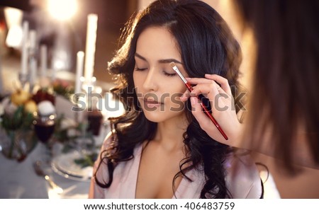 makeup artist preparing bride before the wedding in a morning