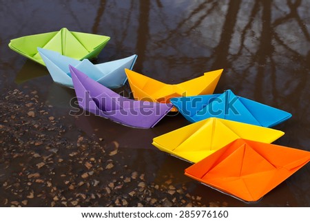 Colorful rainbow paper boats floating in pond
