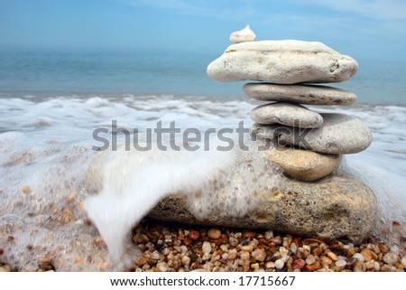 balanced stones in danger against sea waves