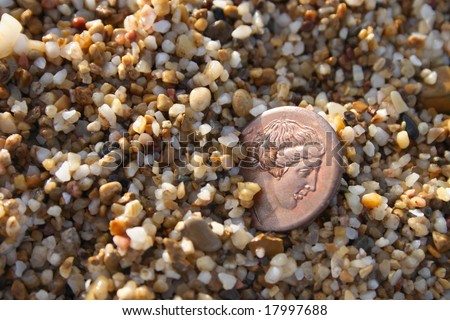 old greek copper coin in sea sand