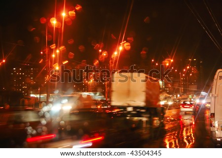 View through car windshield to night road with moving cars. Autumn, rain, reflections.