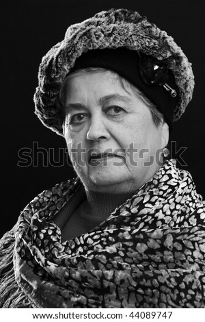 Portrait of senior woman with calm face in hat and shawl over black background