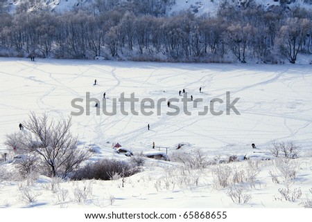Cold winter. Frozen river. Lot of peoples on ice walking, fishing and even swimming in hole.