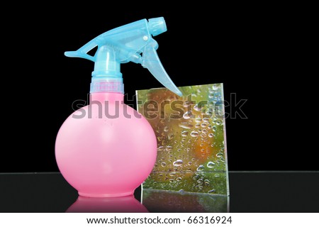 Vivid water concept picture. Plastic spray bottle and some water in it. After spaying at glass - look like living nature. Isolated on black.