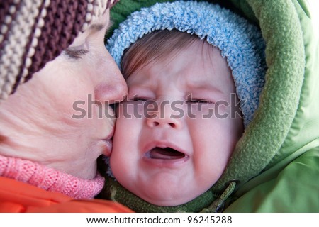 Grandmother soothing and kissing crying baby.