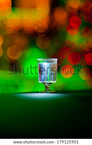 A glass filled with liquor standing on a table with colored bokeh lights in the background