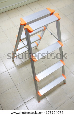orange aluminum folding ladder, stepladder on tile floor for general repair