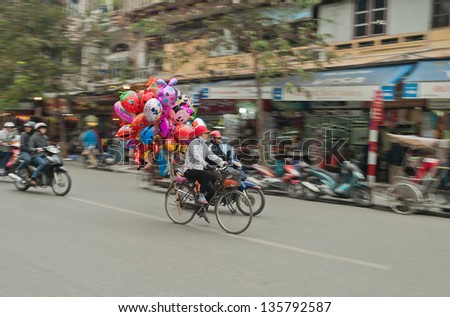 VIETNAM - DECEMBER 12: Woman on a bicycle with balloons on the street on December 12, 2012, in Hanoi, Vietnam. Hanoi is the main economic and cultural center of the country, population of 6.5 million.