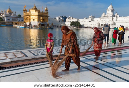 AMRITSAR, INDIA, DEC -7, 2014: Unidentified Indian women and children clean floor near Golden Temple before the evening prayer. Harmandir Sahib is the holiest Sikh gurdwara located in city of Amritsar