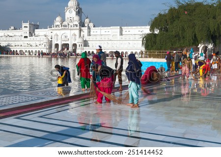 AMRITSAR, INDIA, DEC - 7, 2014: Unidentified Indian women clean floor near Golden Temple before the evening prayer. Harmandir Sahib is the holiest Sikh gurdwara located in the city of Amritsar