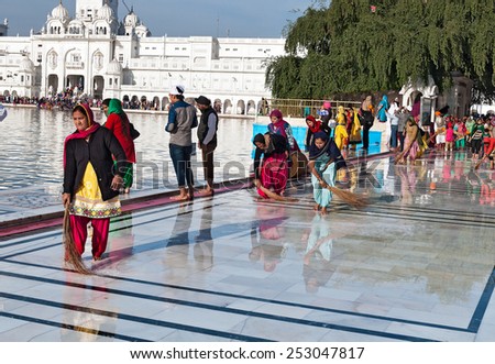 AMRITSAR, INDIA, DEC - 7, 2014: Unidentified Indian women clean floor near Golden Temple before the evening prayer. Harmandir Sahib also Darbar Sahib is the holiest Sikh gurdwara located in Amritsar