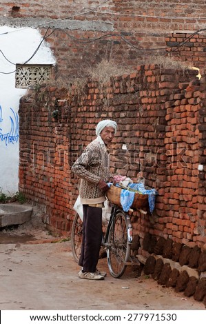 KHAJURAHO, INDIA - DEC 21, 2014: Unidentified Indian old man with bicycle in village. Khajuraho is small town with  Khajuraho Group of Monuments located in the Indian state of Madhya Pradesh