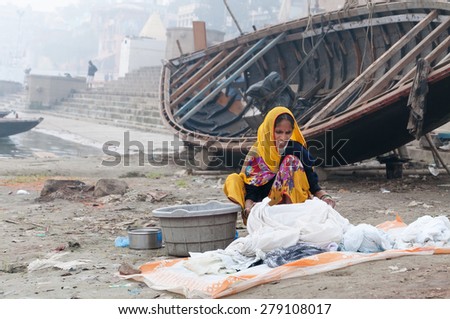 VARANASI, INDIA - DEC 23, 2014: Unidentified Indian woman washes clothes on ghat near sacred river Ganges in Varanasi. Uttar Pradesh, India