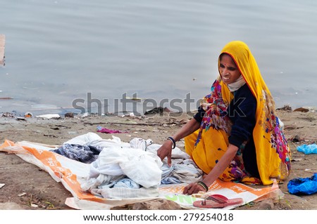 VARANASI, INDIA - DEC 23, 2014: Unidentified Indian woman washes clothes on ghat near sacred river Ganges in Varanasi. Uttar Pradesh, India