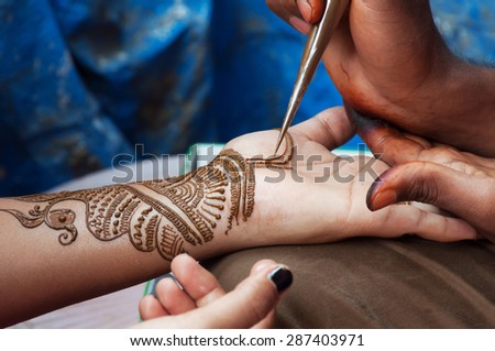 Painting Henna paste on woman\'s hand in the street. India