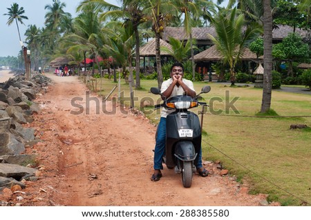KOVALAM, INDIA - DEC 28, 2014: Unidentified Indian man on motorbike on the road next to the Samudra beach. Kovalam. Kerala. India