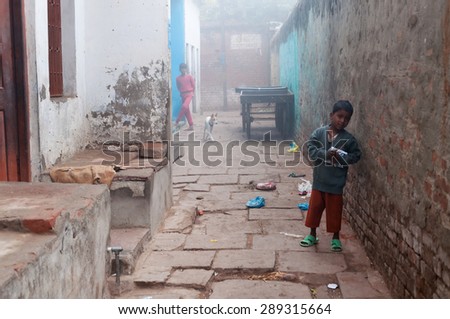 VARANASI, INDIA - DEC 24, 2014: Unidentified Indian boy on the street cold foggy winter morning in Varanasi. Uttar Pradesh. Varanasi  is the holiest of the seven sacred cities in Hinduism and Jainism.