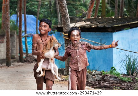 KOVALAM, INDIA - DEC 28, 2014: Unidentified two Indian boys with dog on the street in fishing village. Kovalam. Kerala. India