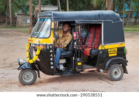 KOVALAM, INDIA - DEC 28, 2014: Indian auto rickshaw with taxi driver man in fishing village. Kovalam. Kerala. India