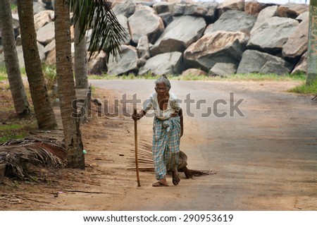 KOVALAM, INDIA - DEC 28, 2014: Unidentified Indian elderly woman walking along the road in the fishing village. Kovalam. Kerala