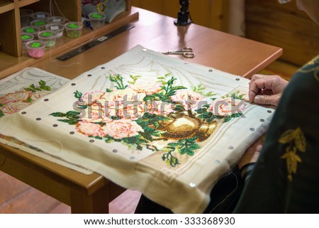 Gorodets,  Russia - May 3, 2015: Girl doing embroidery vase with flowers at City of Craftsmen. Gorodets is the oldest city in the Nizhny Novgorod region, the center of folk art and museum city.