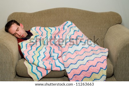 Man sleeping on the couch because he is feeling ill, or maybe he got in trouble with his wife