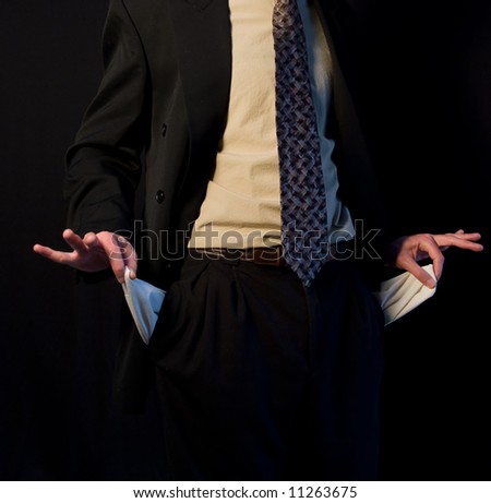 A man in a business suit holding his pockets to show he has no money
