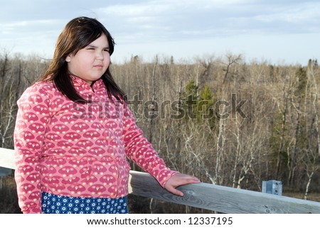 A young girl standing on a hill and looking over the horizon