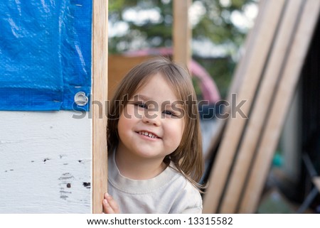 A young girl playing peek-a-boo around a corner