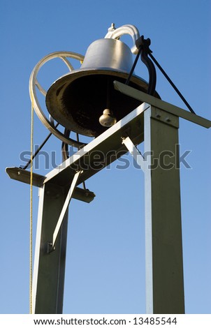 An old school bell shot against a blue sky