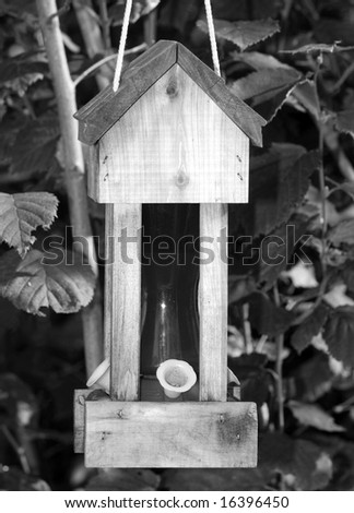 A humming bird feeder shot in black and white, with no birds in the frame