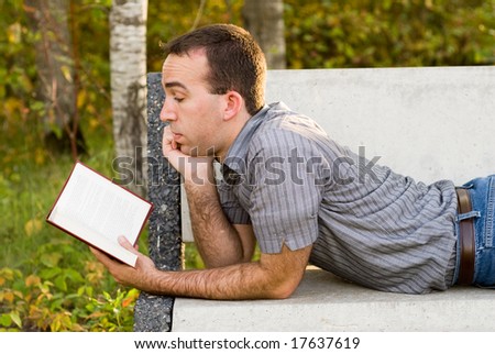 A young man in a park reading a novel