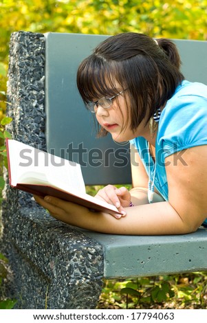 A young girl reading a story book outside