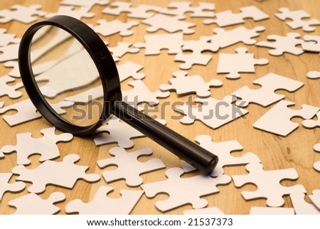 Magnifying glass looking for a piece of the puzzle