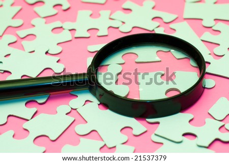 Black magnifying glass searching for the right piece of the puzzle