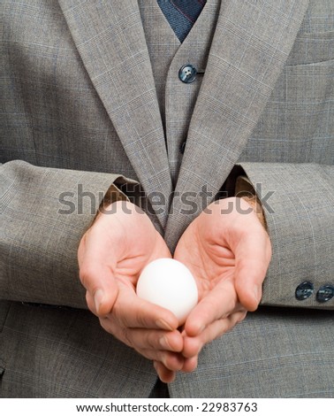 Closeup of a white egg in the hands of a businessman, symbolizing new hope or a new beginning