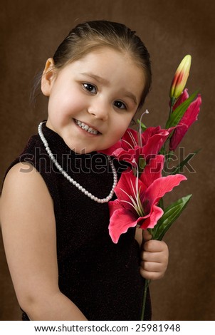 A formal portrait of a young child smiling and wearing some fancy clothing