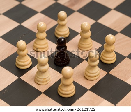 Concept image of racism, with white chess pieces surrounding a black one