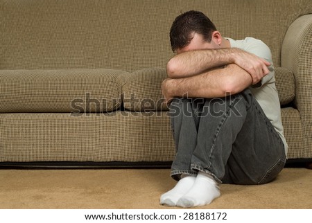 A sad man inside his house, crying into his arm
