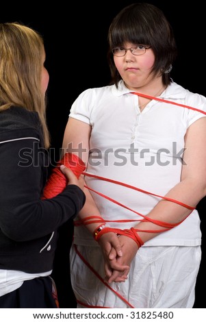 stock photo A young girl being tied up with rope by another girl