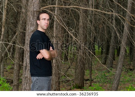 A young man standing in the forest with copyspace to the right