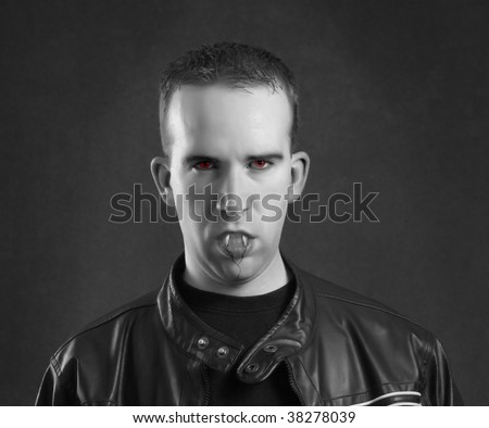 Straight on portrait of a male vampire with his teeth biting his bottom lip
