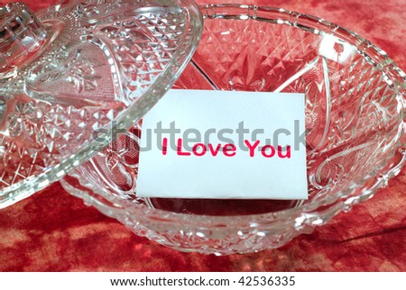 A love letter sitting in a glass candy dish which says, \