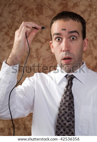 A scared businessman is about to plug a USB cable into the slot on his head