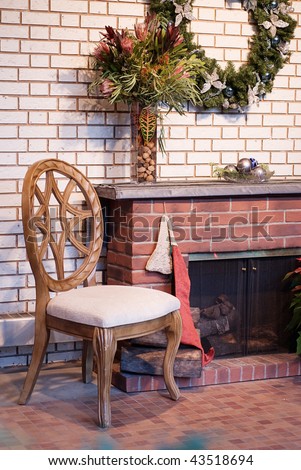 A cozy view of a wooden chair sitting by a brick fireplace